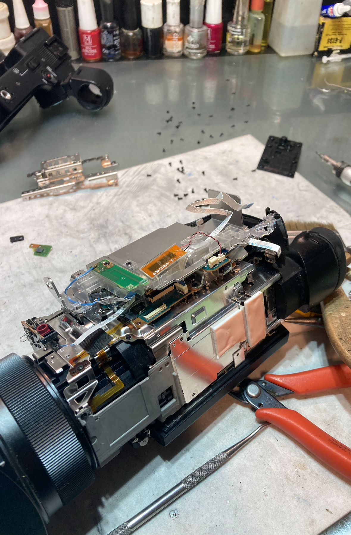 Opened camcorder surrounded by repair tools on the workbench.