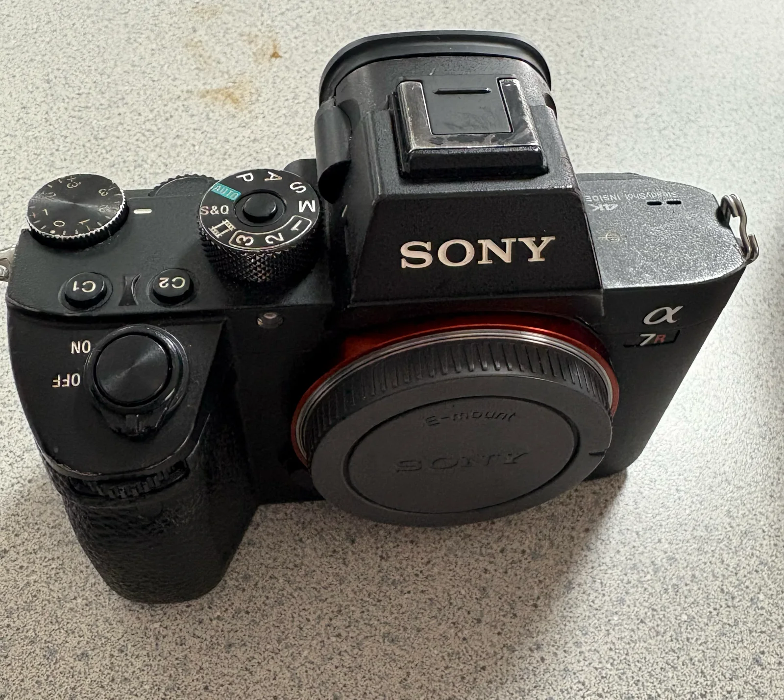 Sony Alpha mirrorless camera body with a body cap on a counter.